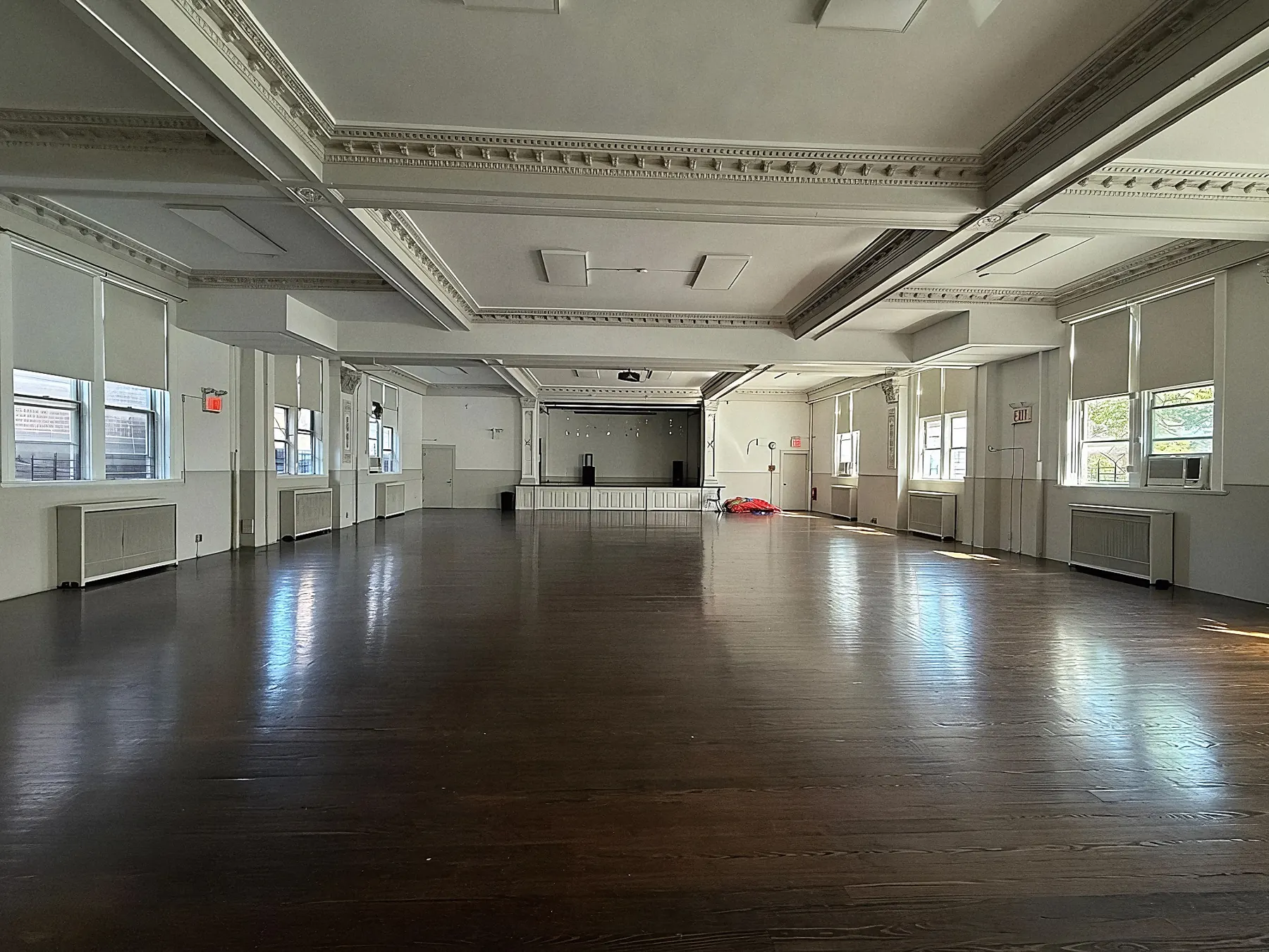 The school's original auditorium, with coffered ceiling, tall windows and an open wooden floor